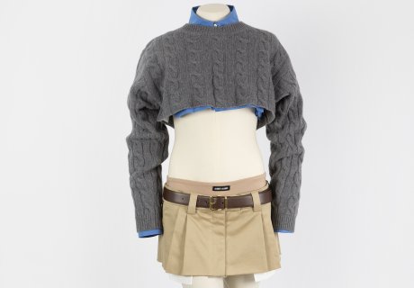 Image: A micro miniskirt paired with a scissored blue cotton shirt and a cropped grey cable knit cashmere sweater. 