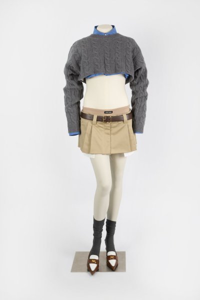 Image: A brown micro miniskirt worn with a belt and a grey cable knit cashmere sweater
