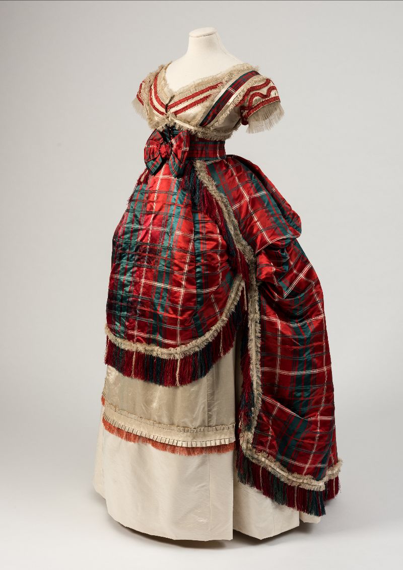 Image: A side view of a red, green and cream silk satin evening dress from 1870