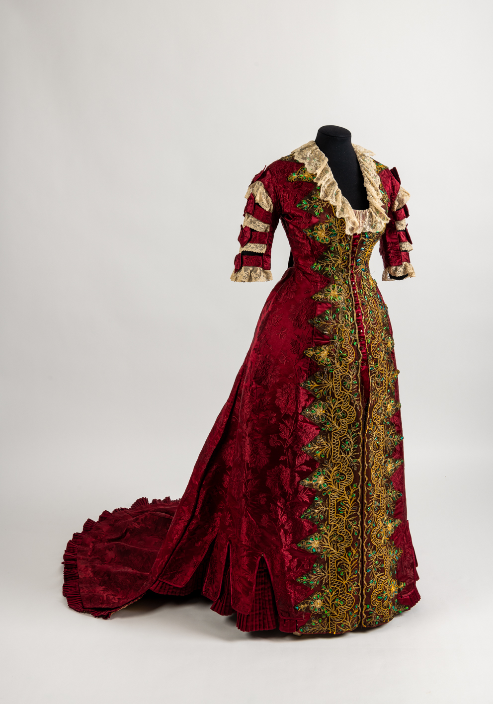 Image: Red silk brocade day dress embroidered with glittering green beetle wing, c.1881