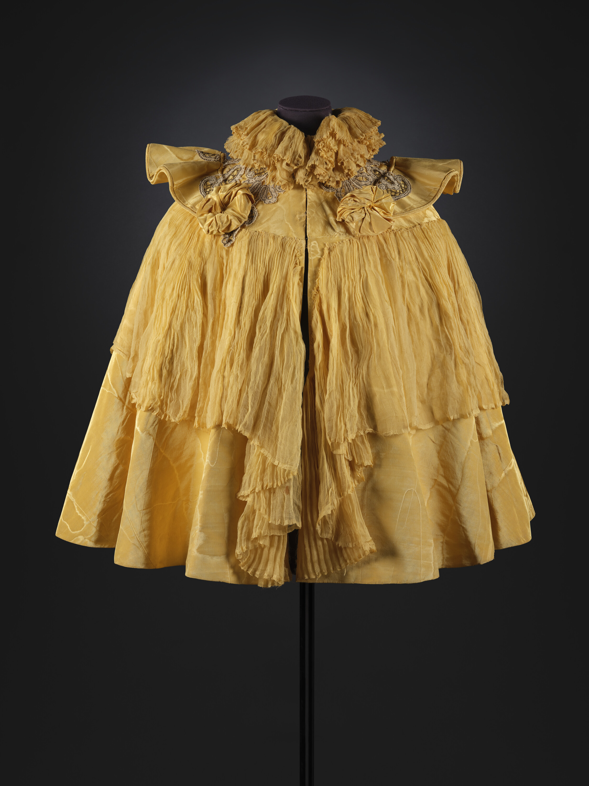 Image: A yellow silk moire cape with upstanding collar and flounce of pleated yellow chiffon. 