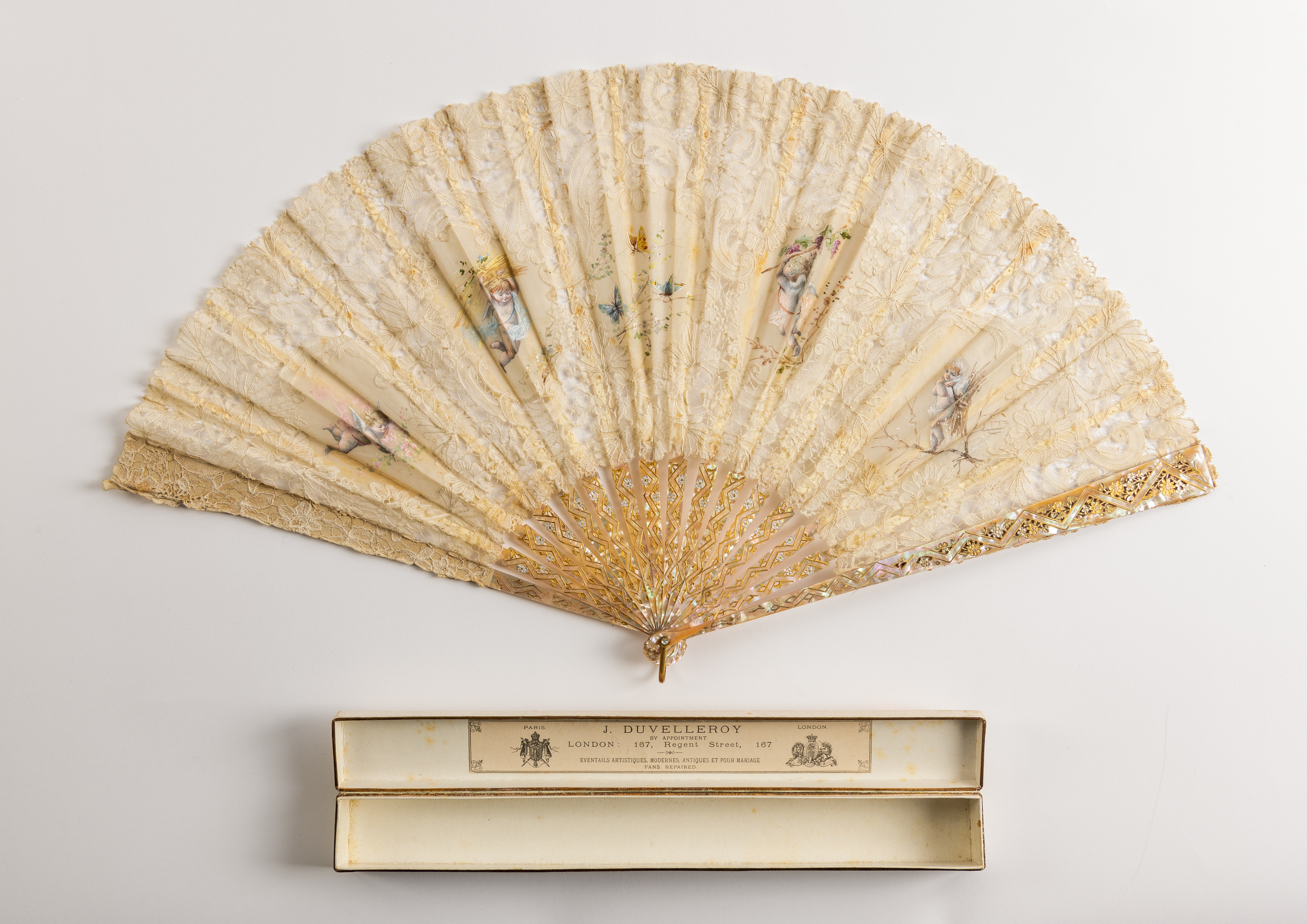 Cream painted silk fan by Duvelleroy with cherub design, inset lace, and mother of pearl sticks and guards