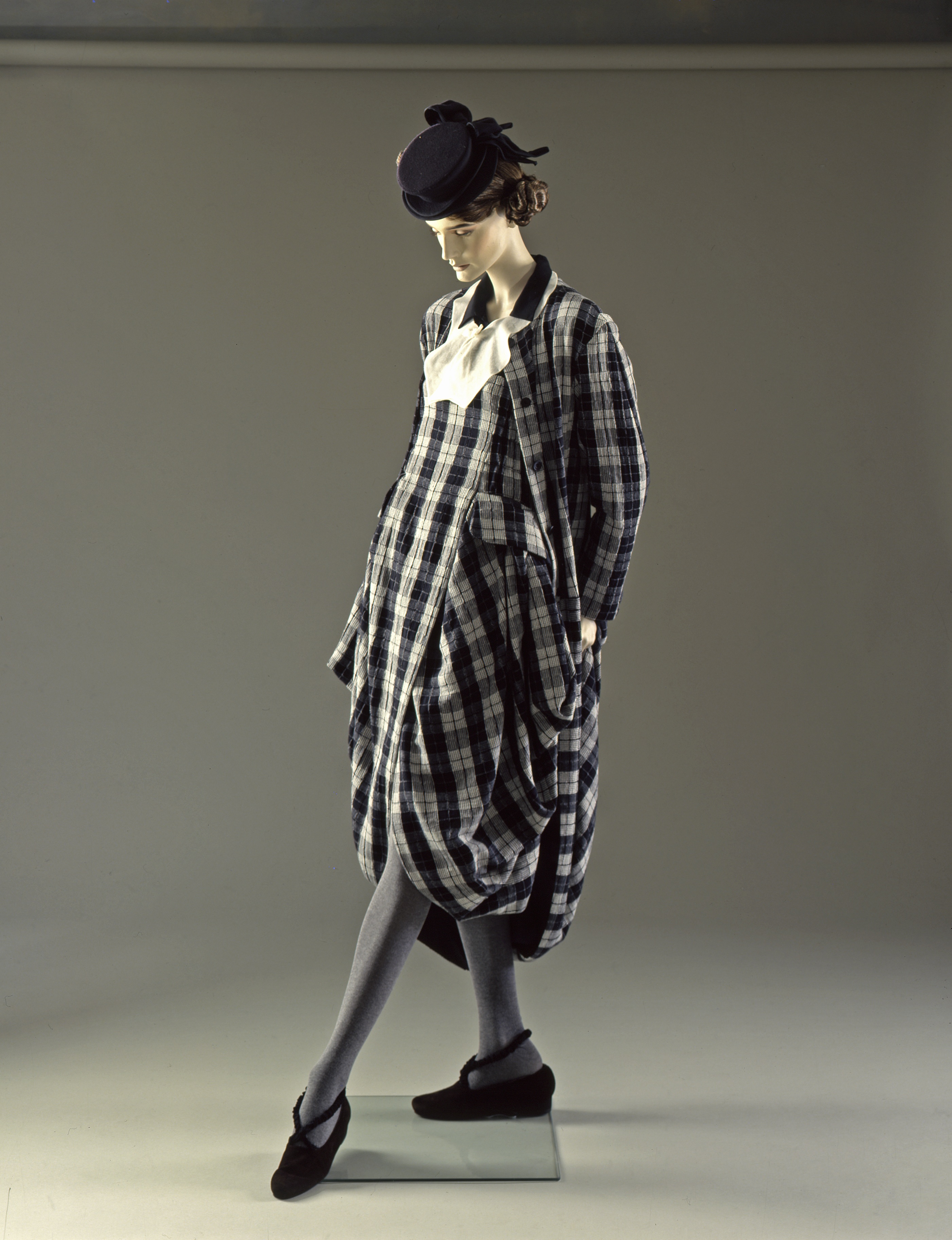 Black and white checked cotton pinafore dress and coat, worn with a dark brown cotton shirt, white cotton organdie collar and a brown felt ‘tilt’ hat by John Galliano, grey tights by Fogal, and brown suede shoes with elastic straps by Patrick Cox