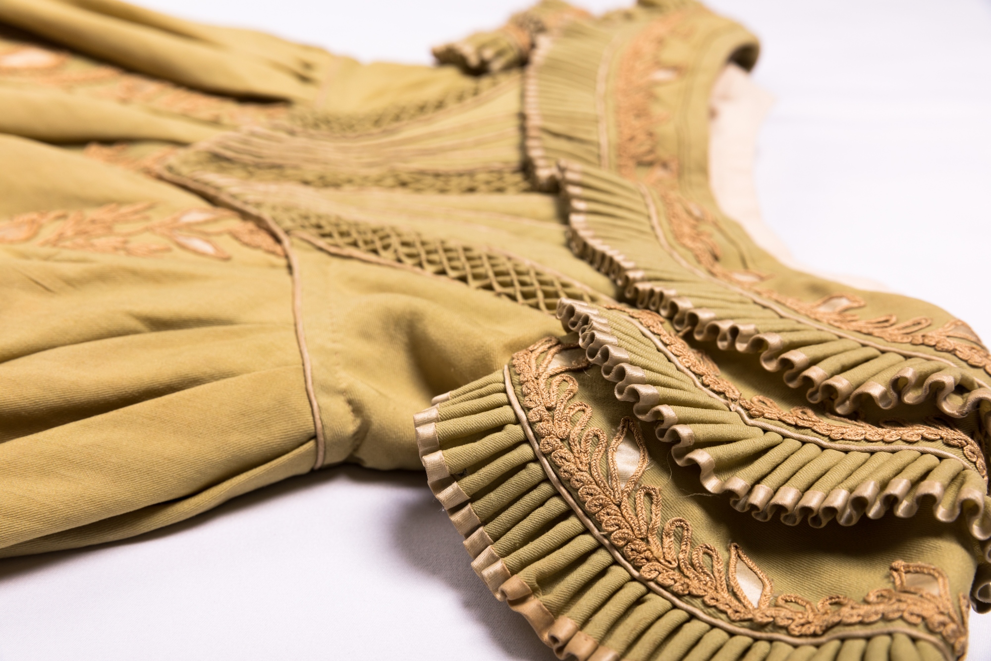 A close up of the shoulder of an 1830s dress showing high quality pleating and embroidery