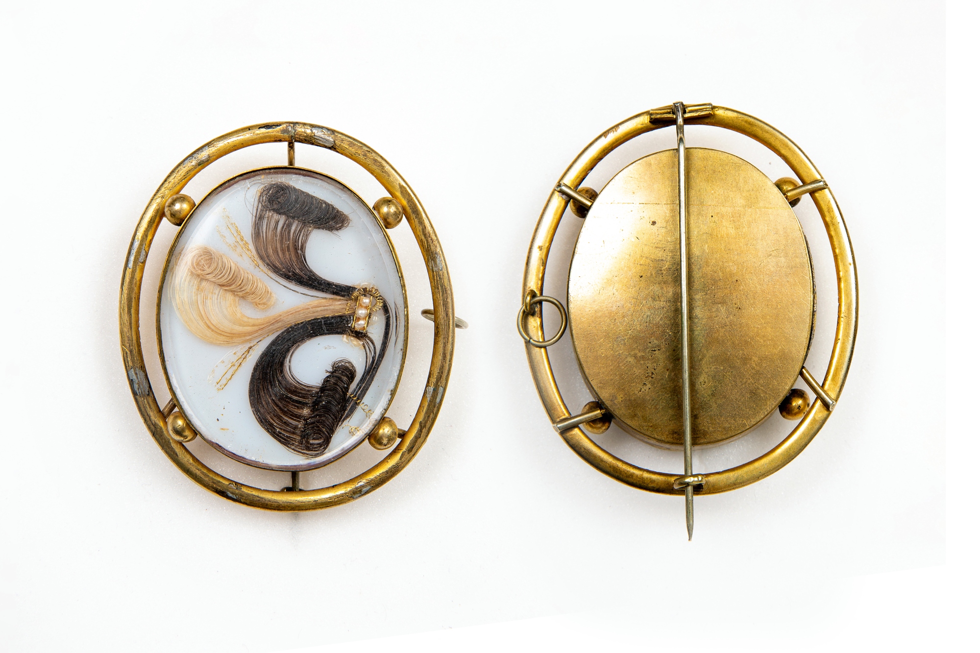An 1880s gold oval brooch with a swirled design on the front created using human hair