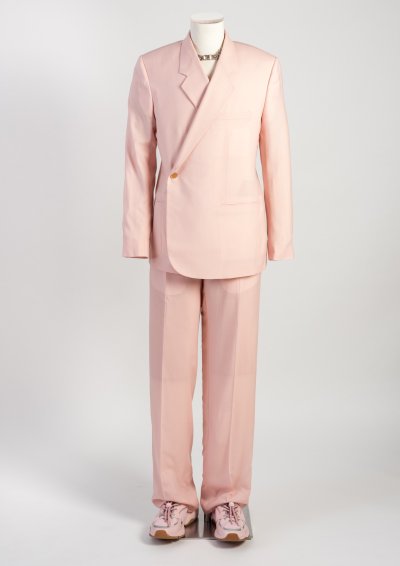 Man’s light pink cashmere twill double-breasted ‘Tailleur Oblique’ jacket and high waist wide trousers, sneakers, necklace and duffle bag