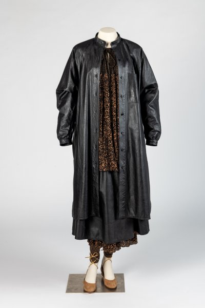Woman’s separates ensemble of printed cotton tunic, skirt and trousers, worn with black leather skirt and coat.